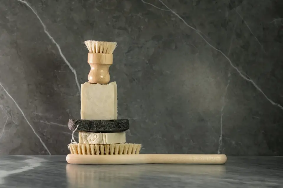 A grooming brush, towel, and dog shampoo laid out near a bathtub